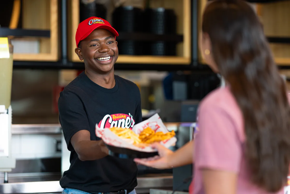 a male employee handing food to the other one