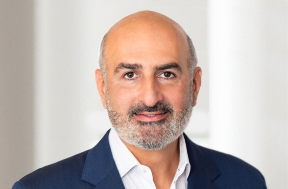 Headshot of a man wearing a navy blazer and white shirt against a light indoor background.
