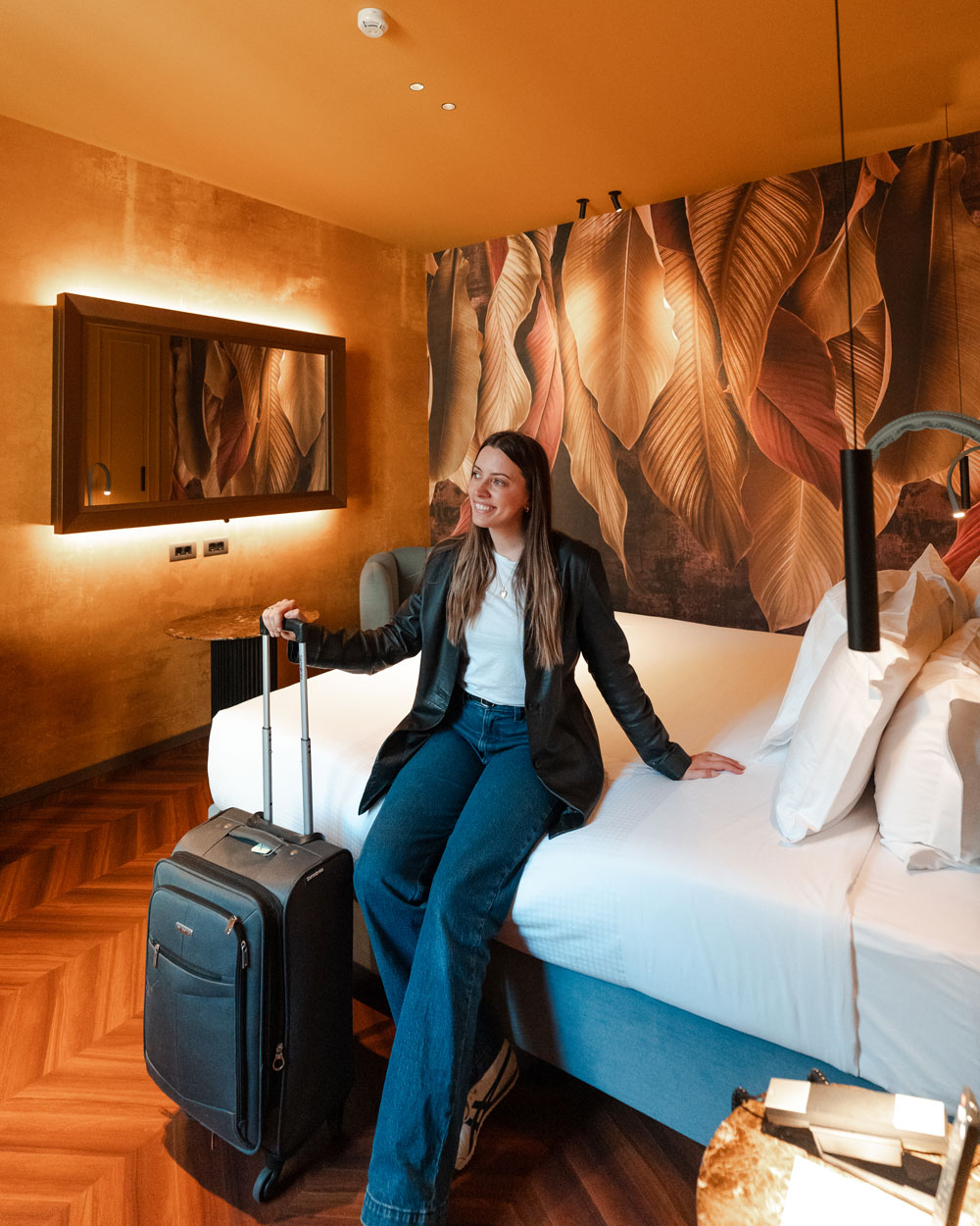 Guest sitting on a hotel bed with luggage