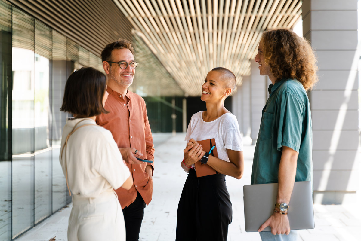 Four coworkers talking outside a modern office building