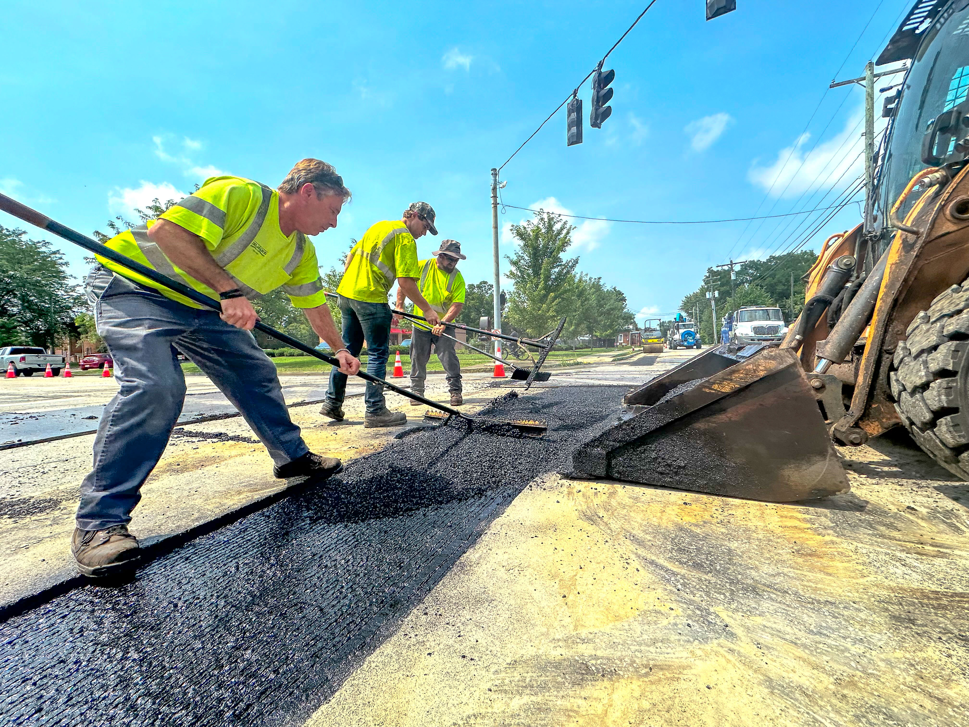 3 men working on asphalt outside