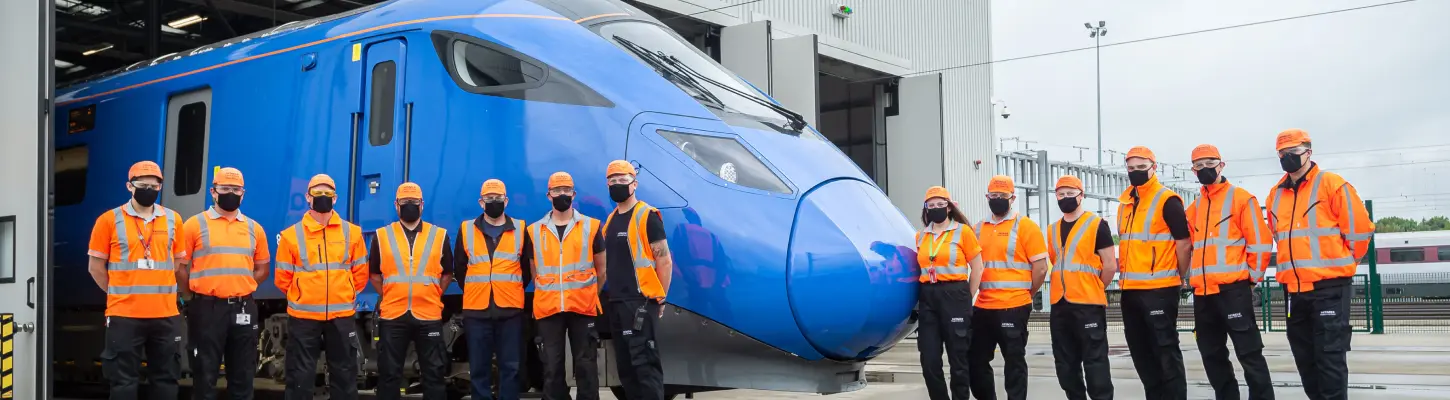 Train maintenance facility with workers inspecting high-speed rail cars