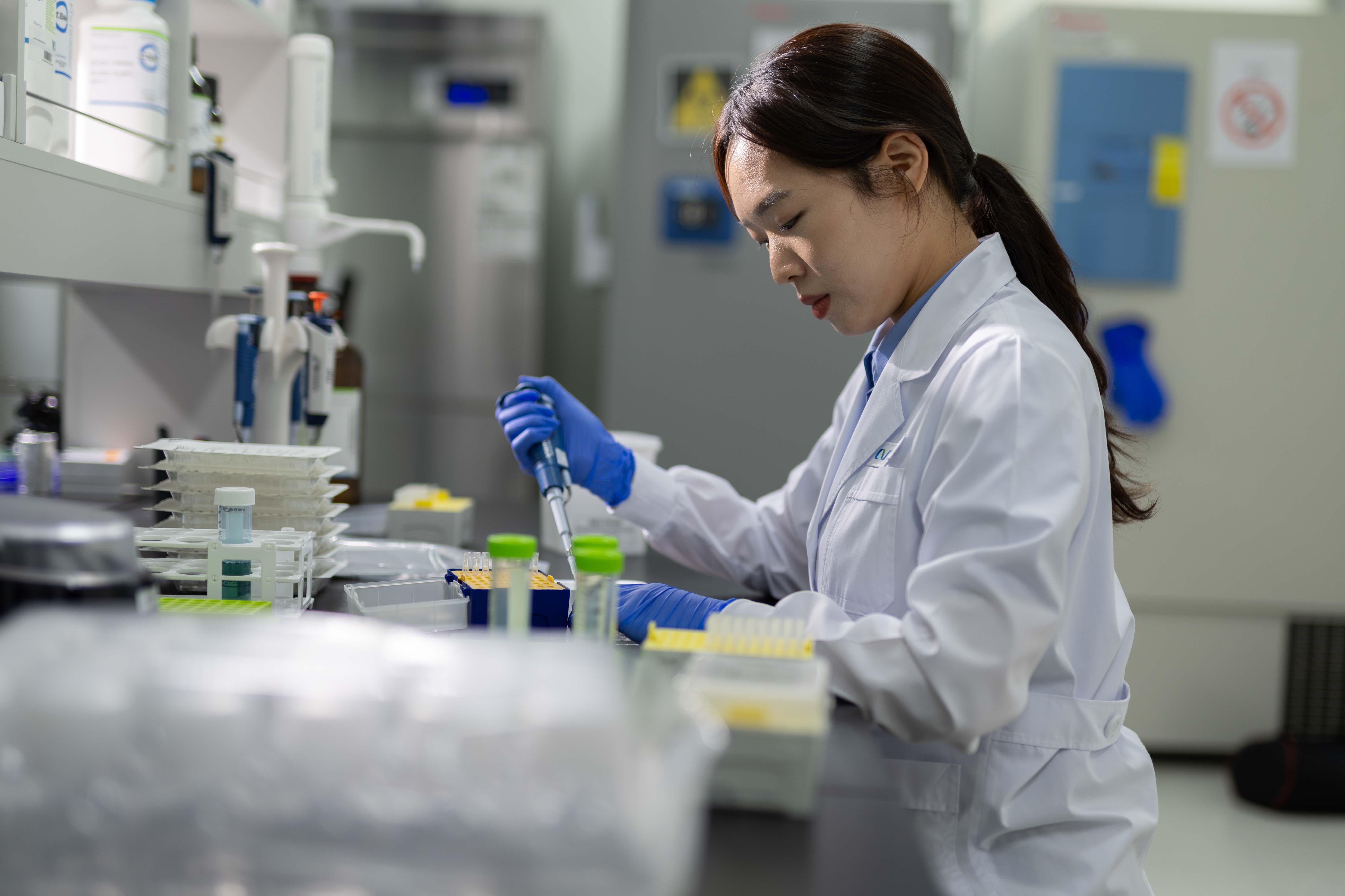 Avantor lab associates in blue lab coats working together with a pipette and sample tray
