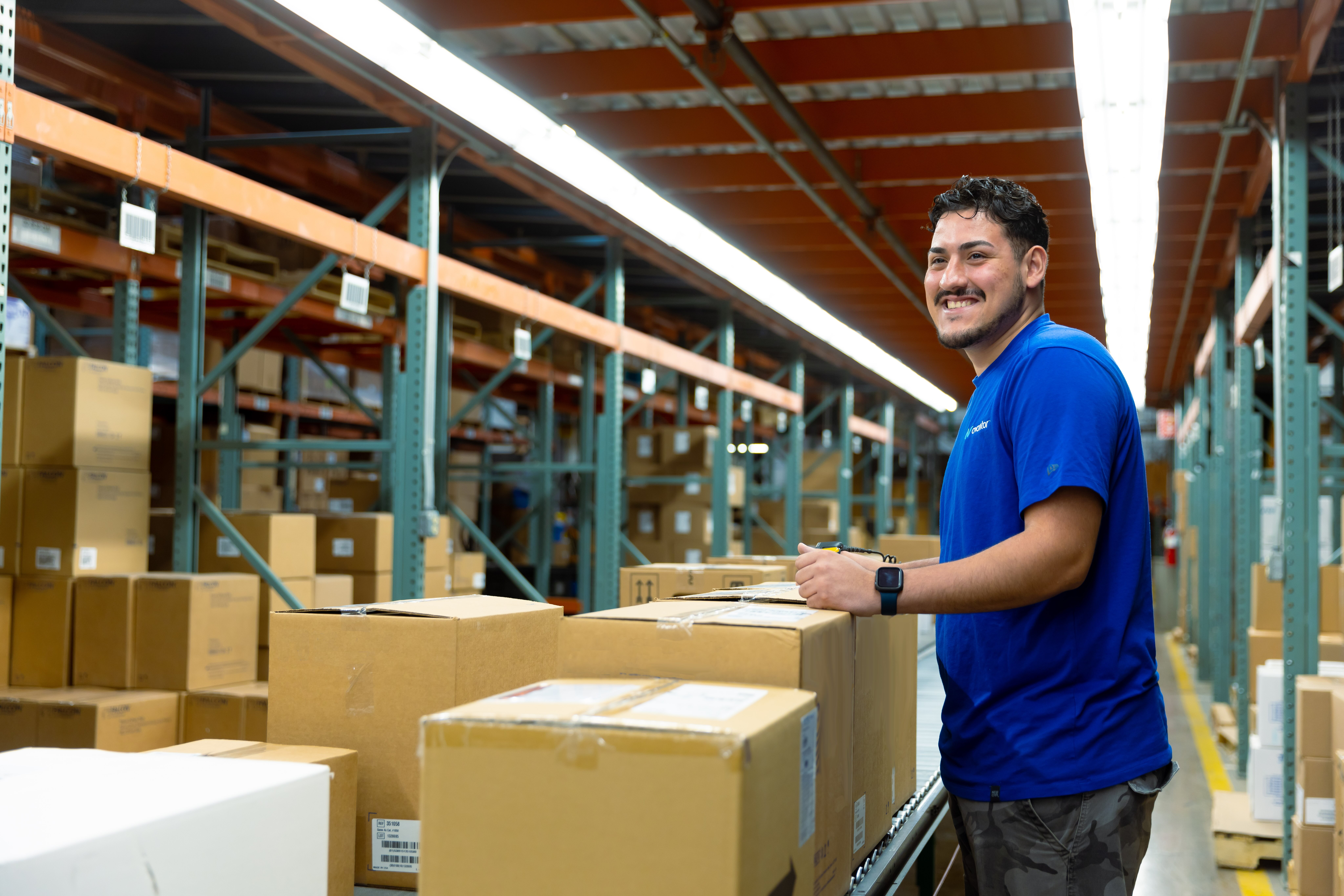 Avantor associate smiling in a warehouse surrounded by shelves of branded boxes