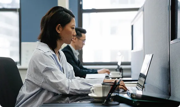 Avantor associate working at a laptop in a modern office with a colleague in the background