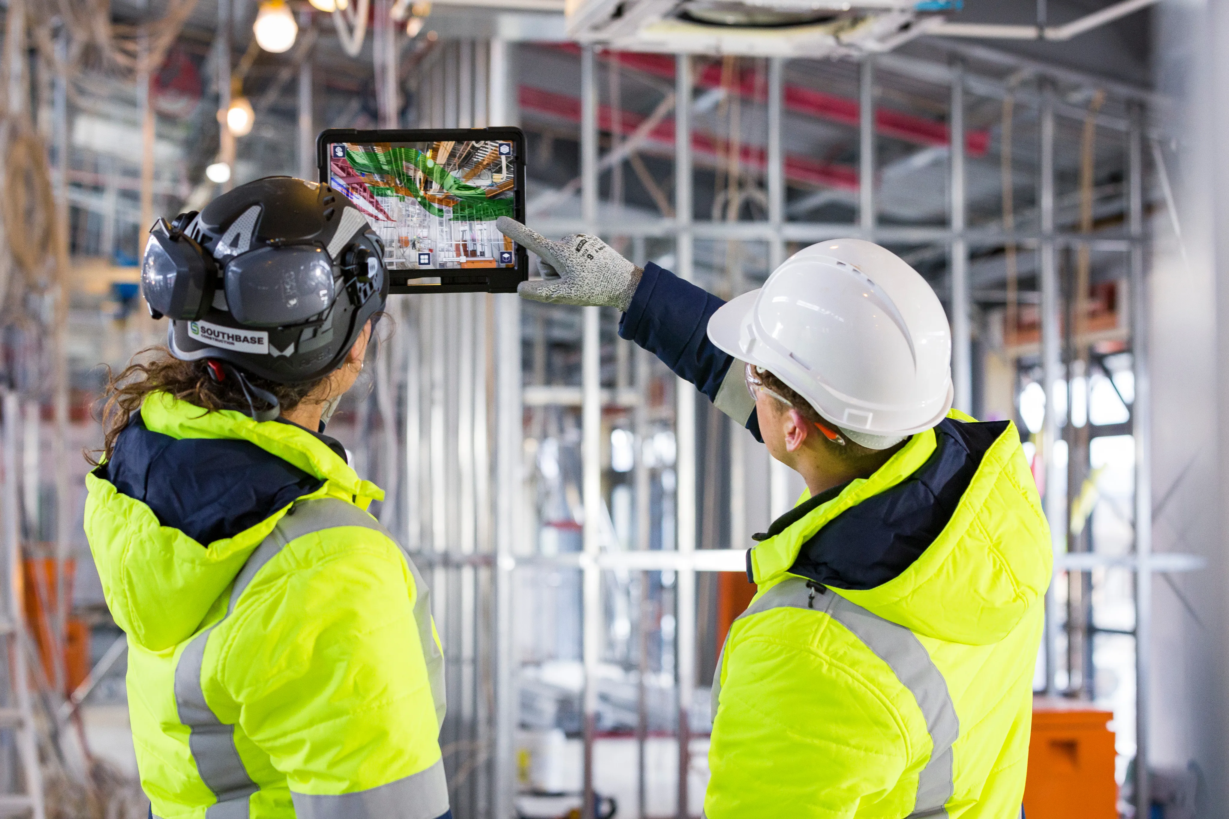 Two Trimble workers reviewing construction data on a tablet at a job site