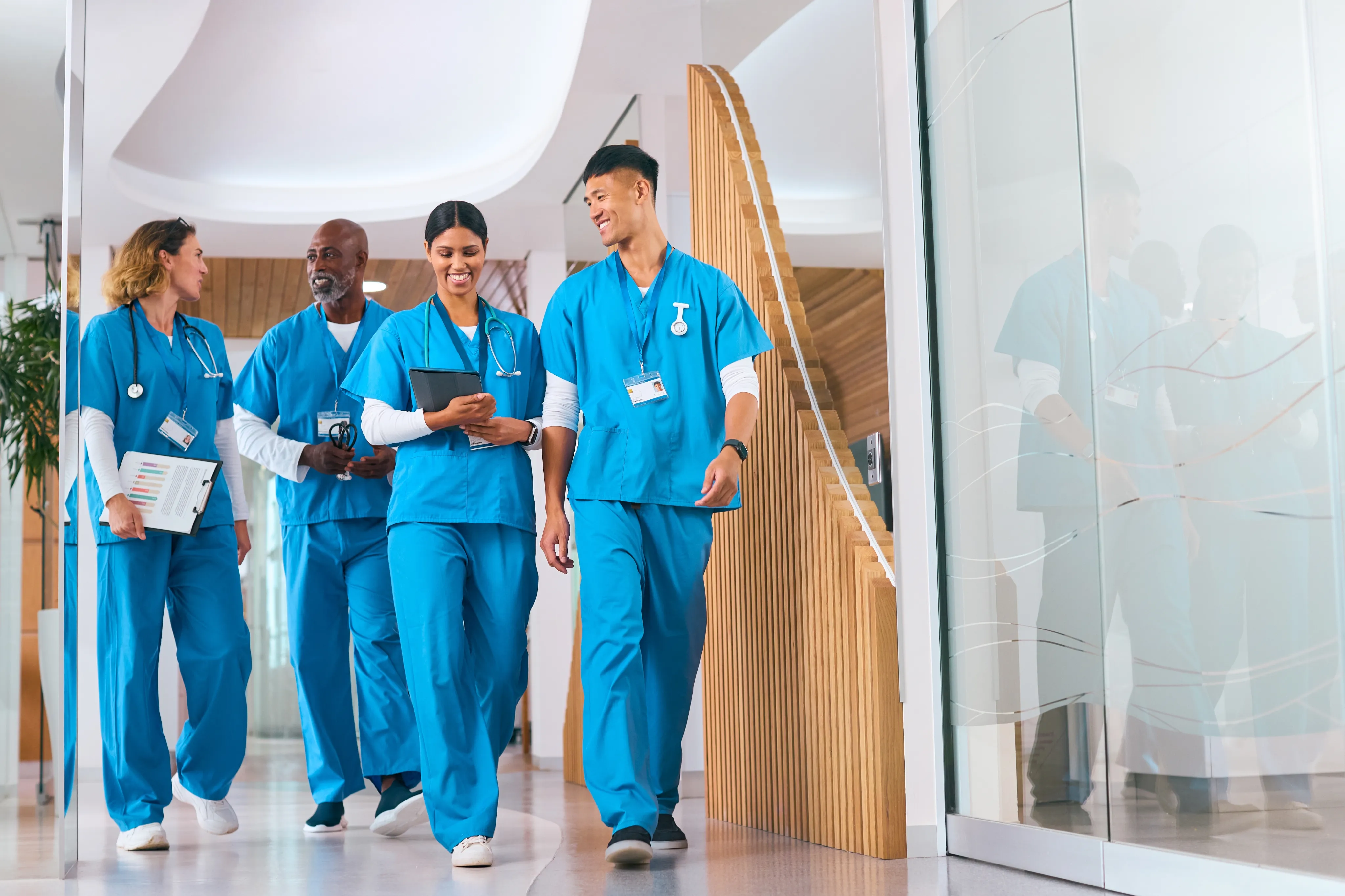 Pharmacy team members in blue scrubs walking together through a hospital hallway