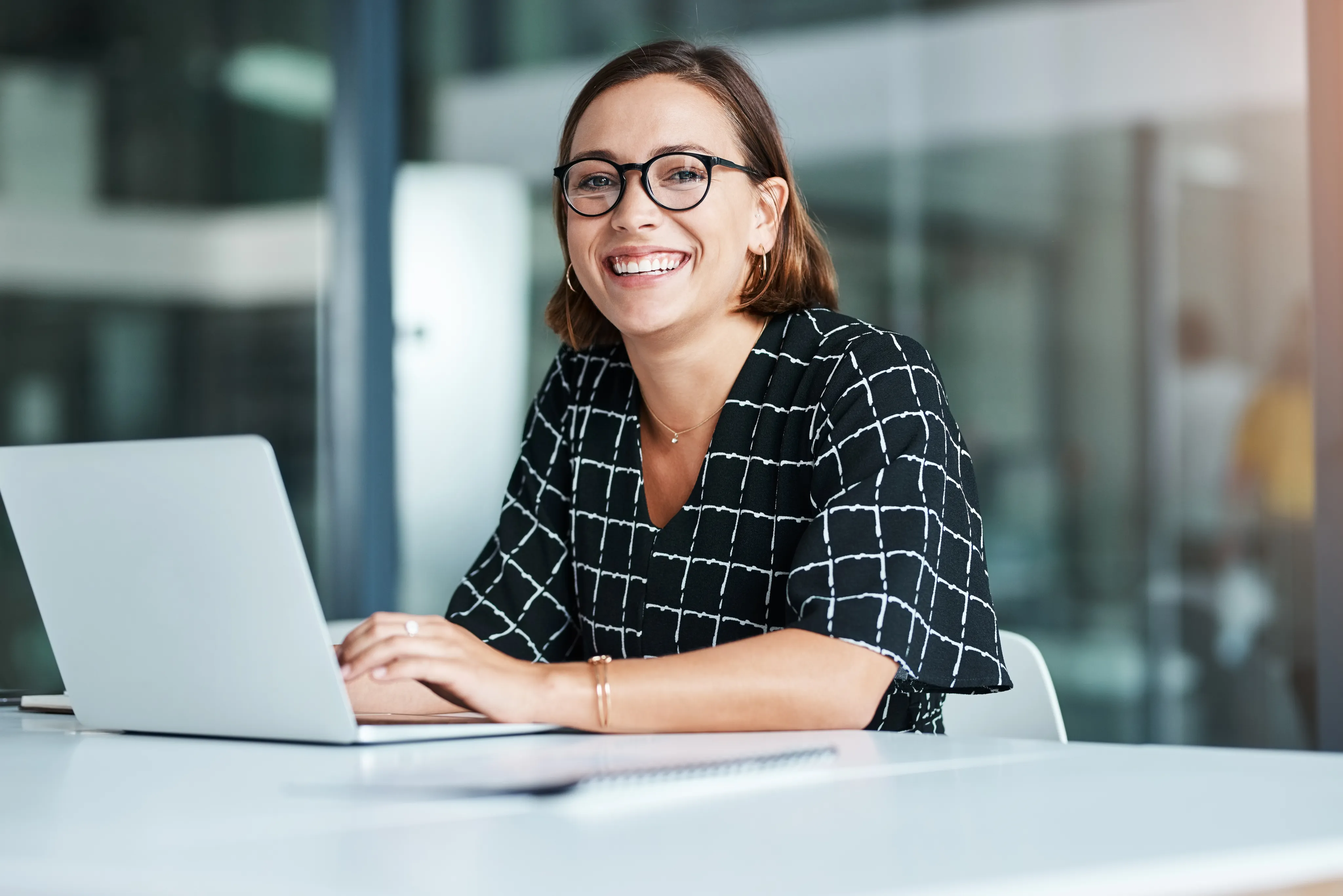 A pharmacist sitting at a laptop and smiling